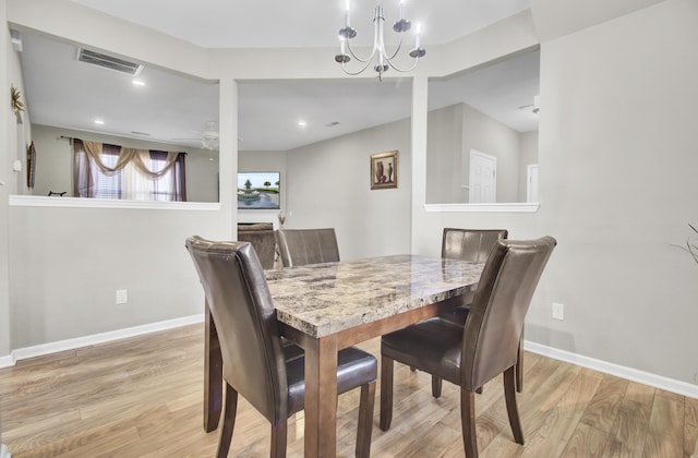 dining room with ceiling fan with notable chandelier and light hardwood / wood-style flooring