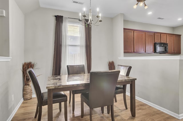 dining room featuring lofted ceiling, light wood-type flooring, and an inviting chandelier