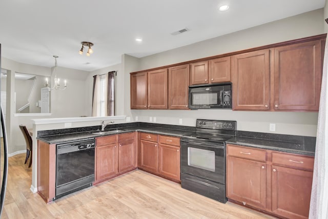 kitchen with light hardwood / wood-style floors, black appliances, sink, an inviting chandelier, and hanging light fixtures