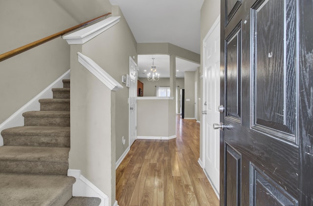 foyer entrance featuring wood-type flooring and an inviting chandelier