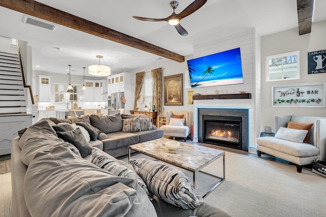 living room featuring ceiling fan, a wealth of natural light, and beamed ceiling