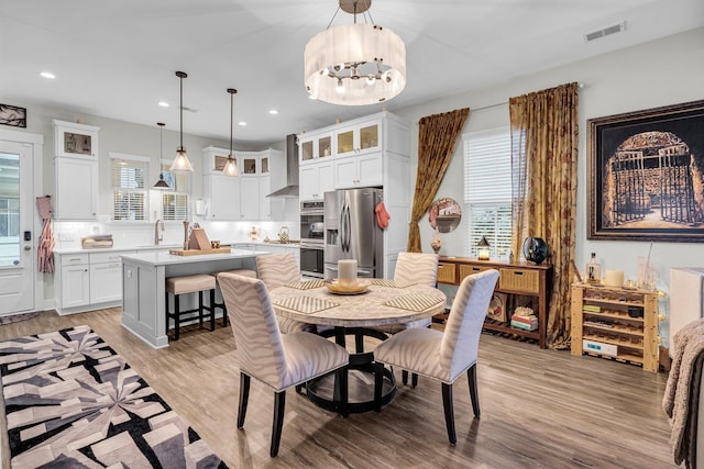 dining area with sink, light hardwood / wood-style floors, and a notable chandelier