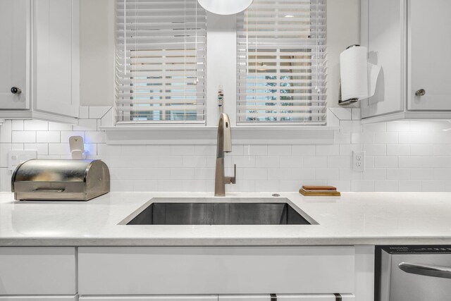 kitchen featuring sink, dishwasher, white cabinetry, light stone counters, and tasteful backsplash