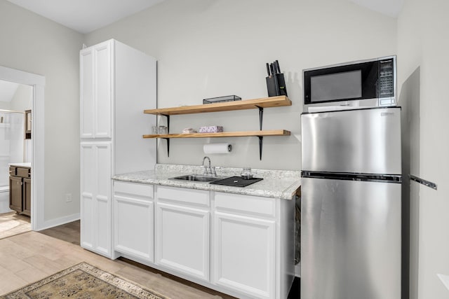 kitchen with stainless steel appliances, white cabinetry, sink, and light hardwood / wood-style floors