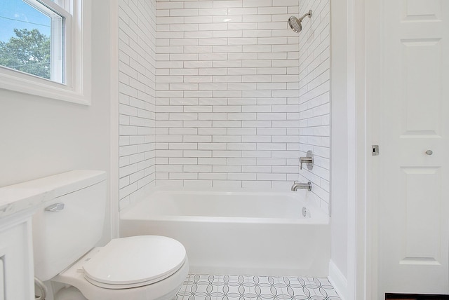 bathroom featuring tile patterned floors, tiled shower / bath combo, and toilet