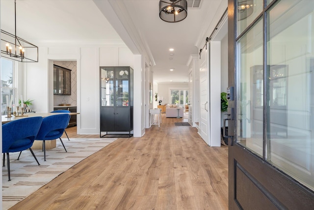 entrance foyer with a barn door, light wood-style flooring, a notable chandelier, and recessed lighting