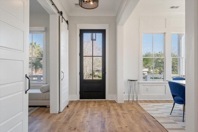 entryway featuring visible vents, a barn door, a wealth of natural light, and light wood-style floors