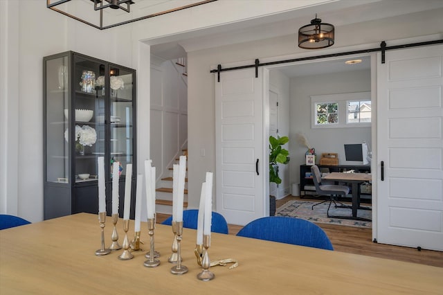 dining space with a barn door, stairway, and wood finished floors