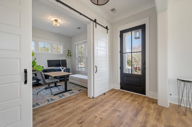 office space with a healthy amount of sunlight, light wood-style floors, a barn door, and visible vents