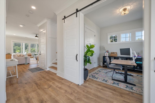 office with recessed lighting, a barn door, ornamental molding, light wood-type flooring, and baseboards