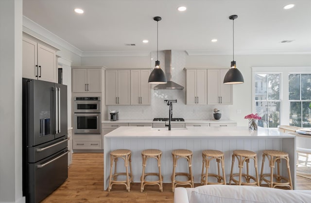 kitchen featuring tasteful backsplash, wall chimney exhaust hood, ornamental molding, stainless steel appliances, and light countertops