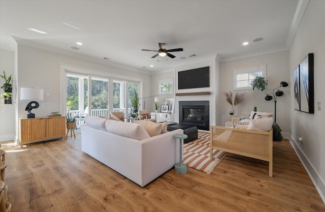 living room featuring recessed lighting, crown molding, light wood-style flooring, and baseboards