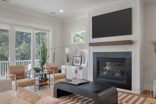 living area featuring visible vents, crown molding, light wood-style floors, a fireplace, and recessed lighting