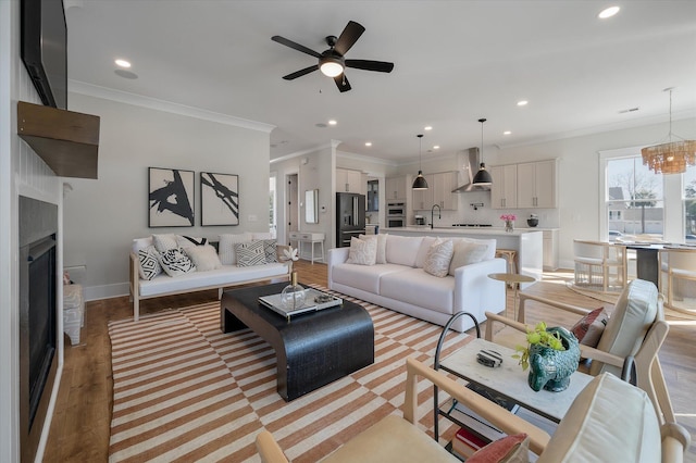 living room featuring crown molding, recessed lighting, a fireplace, and baseboards