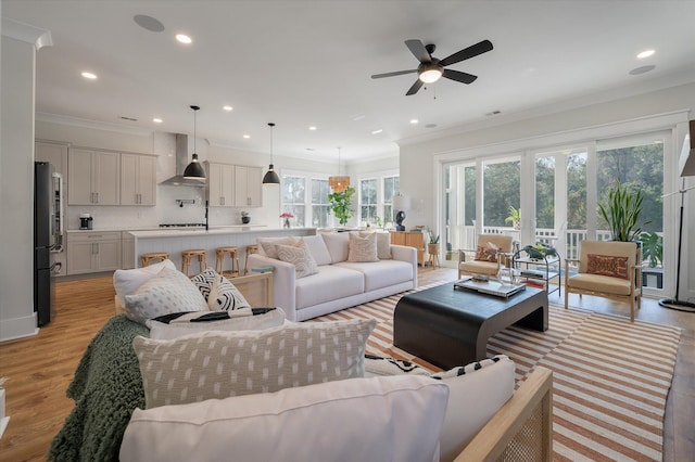 living room with ornamental molding, light wood-type flooring, a ceiling fan, and recessed lighting