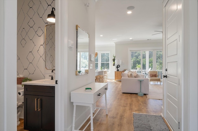 interior space with baseboards, an accent wall, ornamental molding, wood finished floors, and recessed lighting