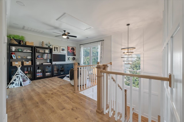 corridor featuring visible vents, attic access, ornamental molding, an upstairs landing, and wood finished floors