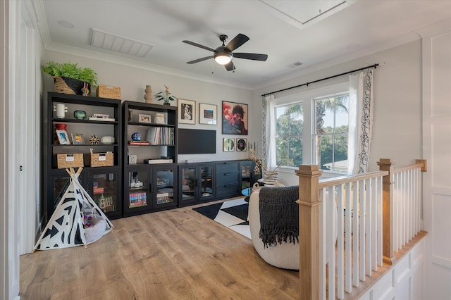 interior space with attic access, crown molding, visible vents, and wood finished floors