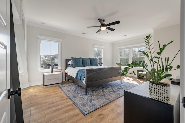 bedroom with light wood-style floors, multiple windows, and crown molding