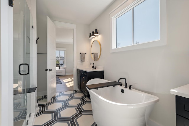 full bath featuring a stall shower, a soaking tub, vanity, and baseboards