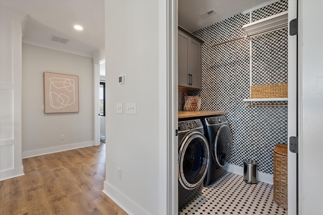 washroom featuring visible vents, cabinet space, wood finished floors, independent washer and dryer, and baseboards