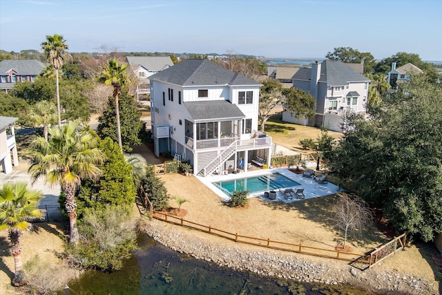 rear view of property with a fenced backyard, stairs, roof with shingles, a fenced in pool, and a patio area