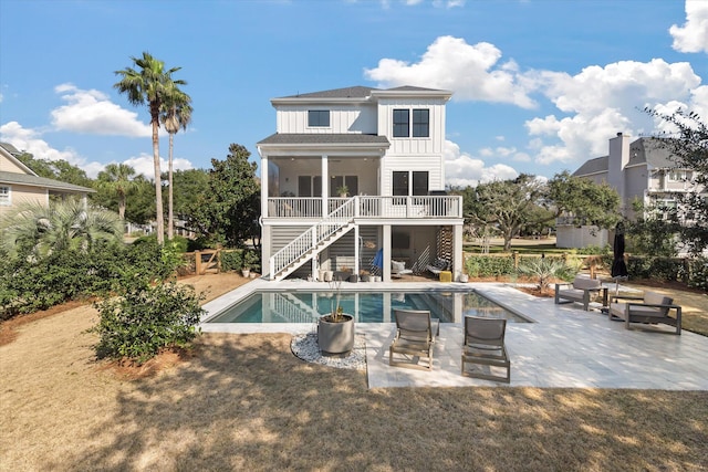 back of house featuring board and batten siding, a patio area, an outdoor pool, and stairs