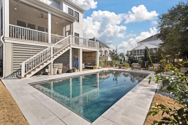 outdoor pool with a patio area, stairway, and a ceiling fan