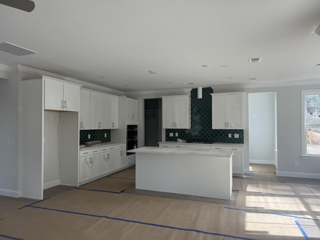 kitchen with pendant lighting, a kitchen island, decorative backsplash, light wood-type flooring, and white cabinets