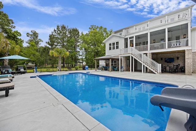 view of pool with ceiling fan, stairs, a water slide, a patio, and fence
