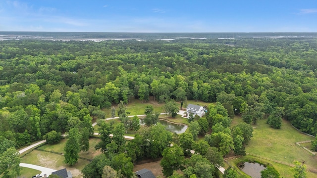 aerial view of property and surrounding area featuring a heavily wooded area and a large body of water