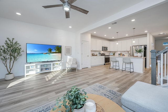 living room with ceiling fan and light hardwood / wood-style floors