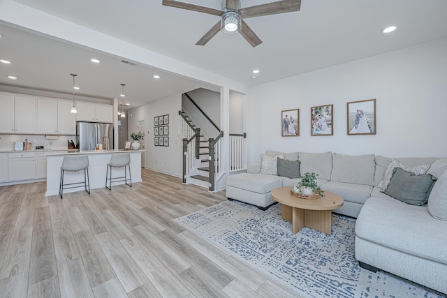 living room with ceiling fan and light hardwood / wood-style flooring