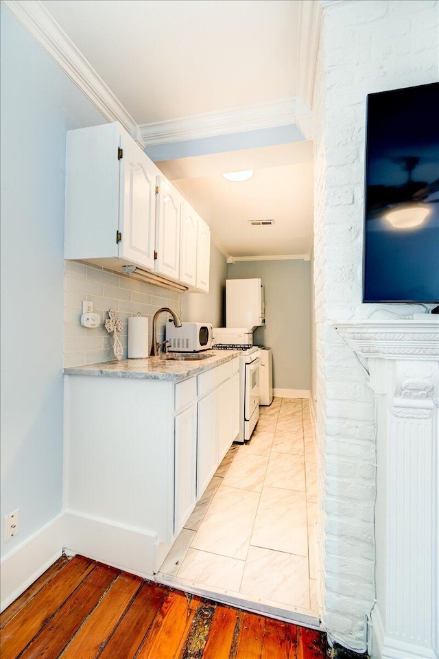 kitchen with white appliances, ornamental molding, light hardwood / wood-style floors, and backsplash