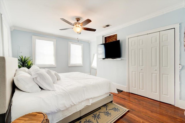 bedroom with dark hardwood / wood-style flooring, ornamental molding, ceiling fan, and a closet