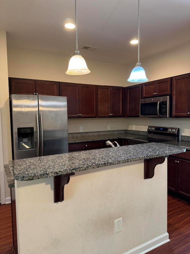 kitchen featuring a breakfast bar, dark hardwood / wood-style flooring, and appliances with stainless steel finishes