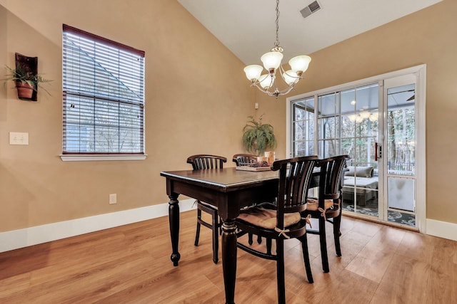 dining area featuring an inviting chandelier, vaulted ceiling, and light hardwood / wood-style floors