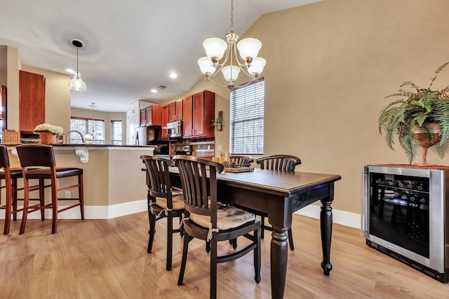 dining room featuring light wood-type flooring, vaulted ceiling, wine cooler, and a notable chandelier