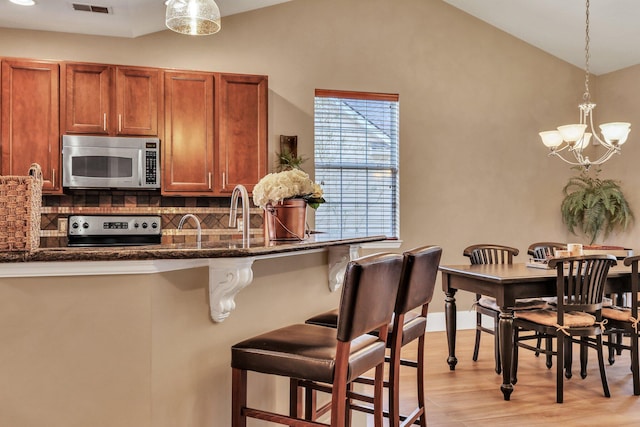 kitchen featuring decorative light fixtures, decorative backsplash, a breakfast bar, and appliances with stainless steel finishes