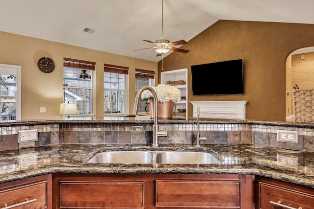 kitchen featuring sink, ceiling fan, dark stone countertops, and lofted ceiling