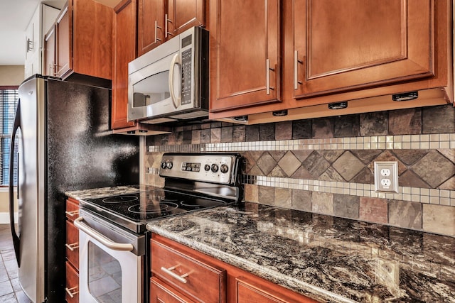 kitchen with tasteful backsplash, dark stone counters, and stainless steel appliances