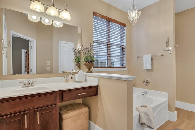 bathroom featuring wood-type flooring, a tub to relax in, vanity, and a notable chandelier