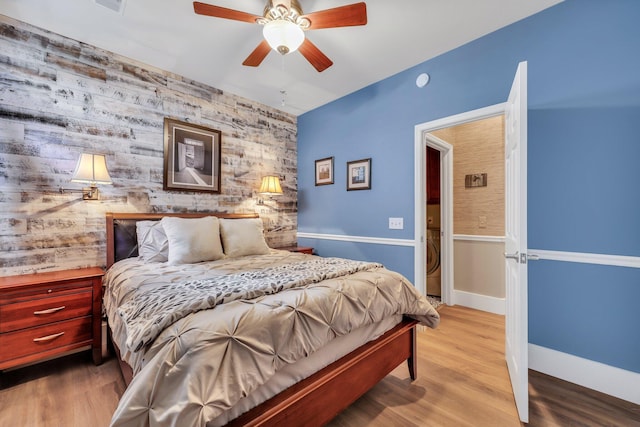 bedroom featuring ceiling fan, wooden walls, and light hardwood / wood-style floors