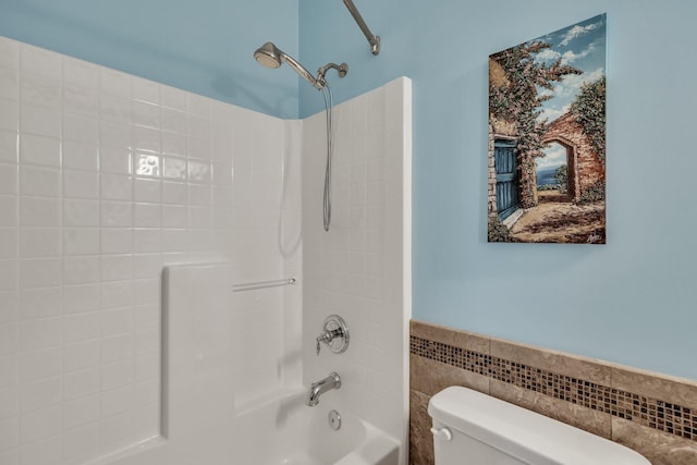 bathroom with toilet, shower / bath combination, and tile walls