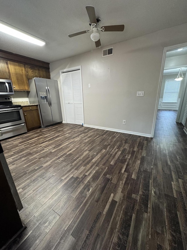 kitchen featuring a textured ceiling, stainless steel appliances, ceiling fan, and dark wood-type flooring