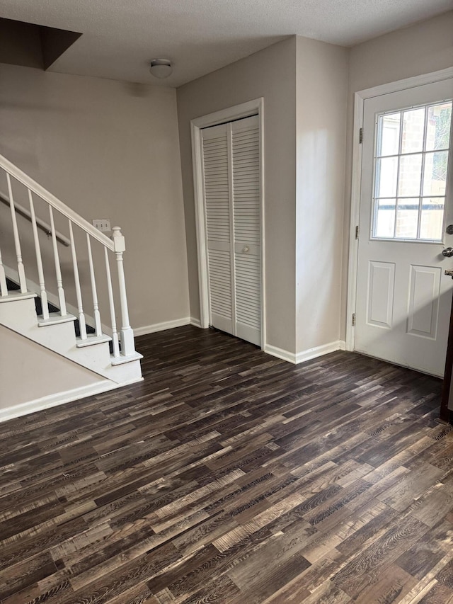 entryway with dark wood-type flooring and a textured ceiling