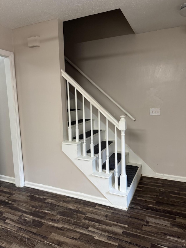 stairs featuring a textured ceiling and hardwood / wood-style flooring