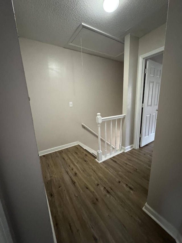 hallway with dark wood-type flooring and a textured ceiling