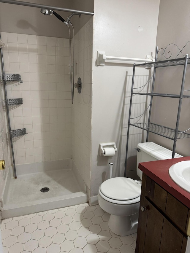 bathroom featuring a tile shower, tile patterned floors, vanity, and toilet