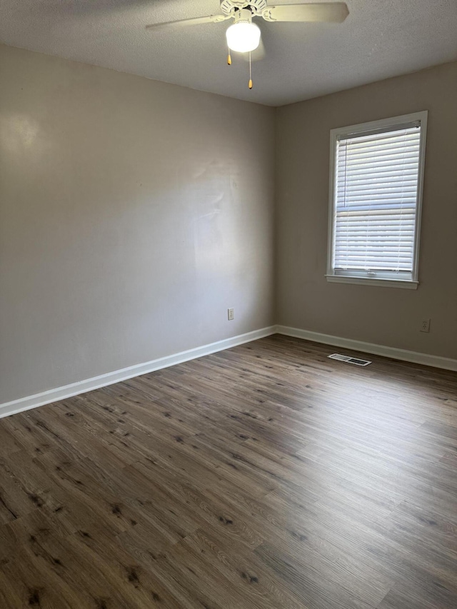 empty room featuring a textured ceiling, ceiling fan, and dark hardwood / wood-style floors